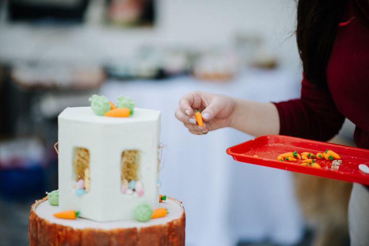 A decorator finishing a white celebration cake with fresh toppings